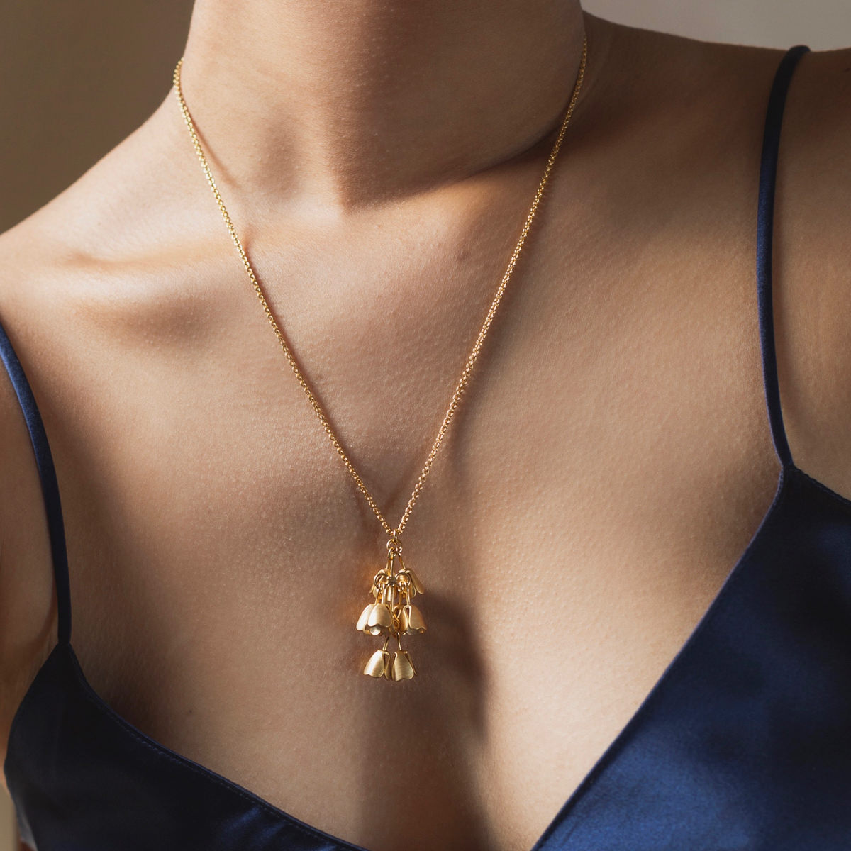 Close up of Brave Edith gold Padauk necklace on woman wearing navy silk top